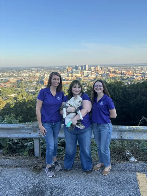 Compassionate Crossings team members with Morty overlooking the Birmingham skyline